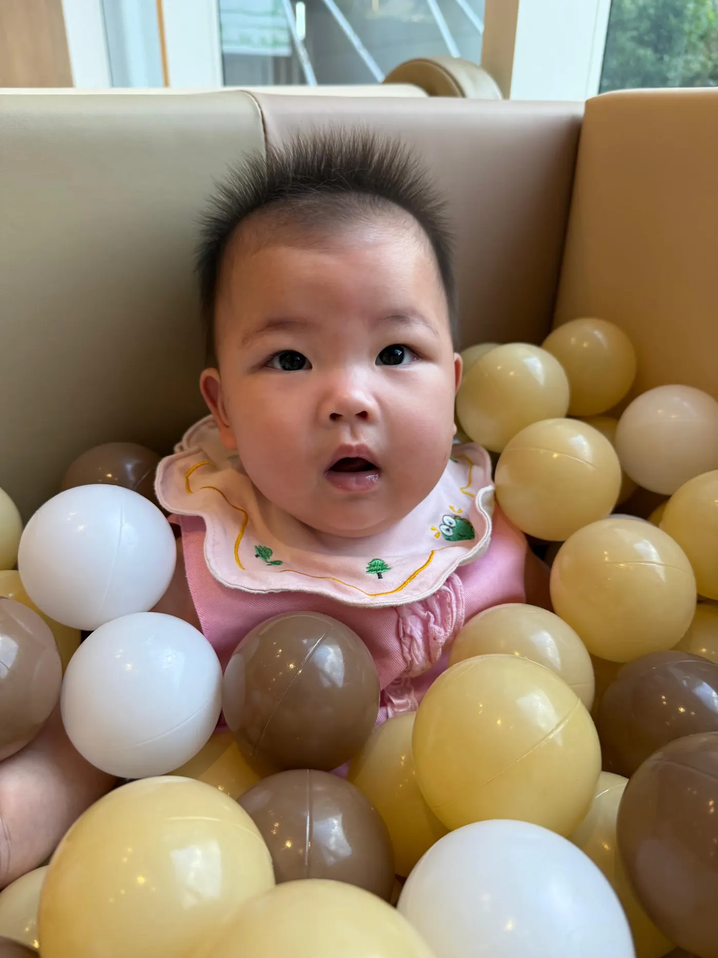A parent holding their baby up at Naru Play Café, showing them the wooden pretend-play area.