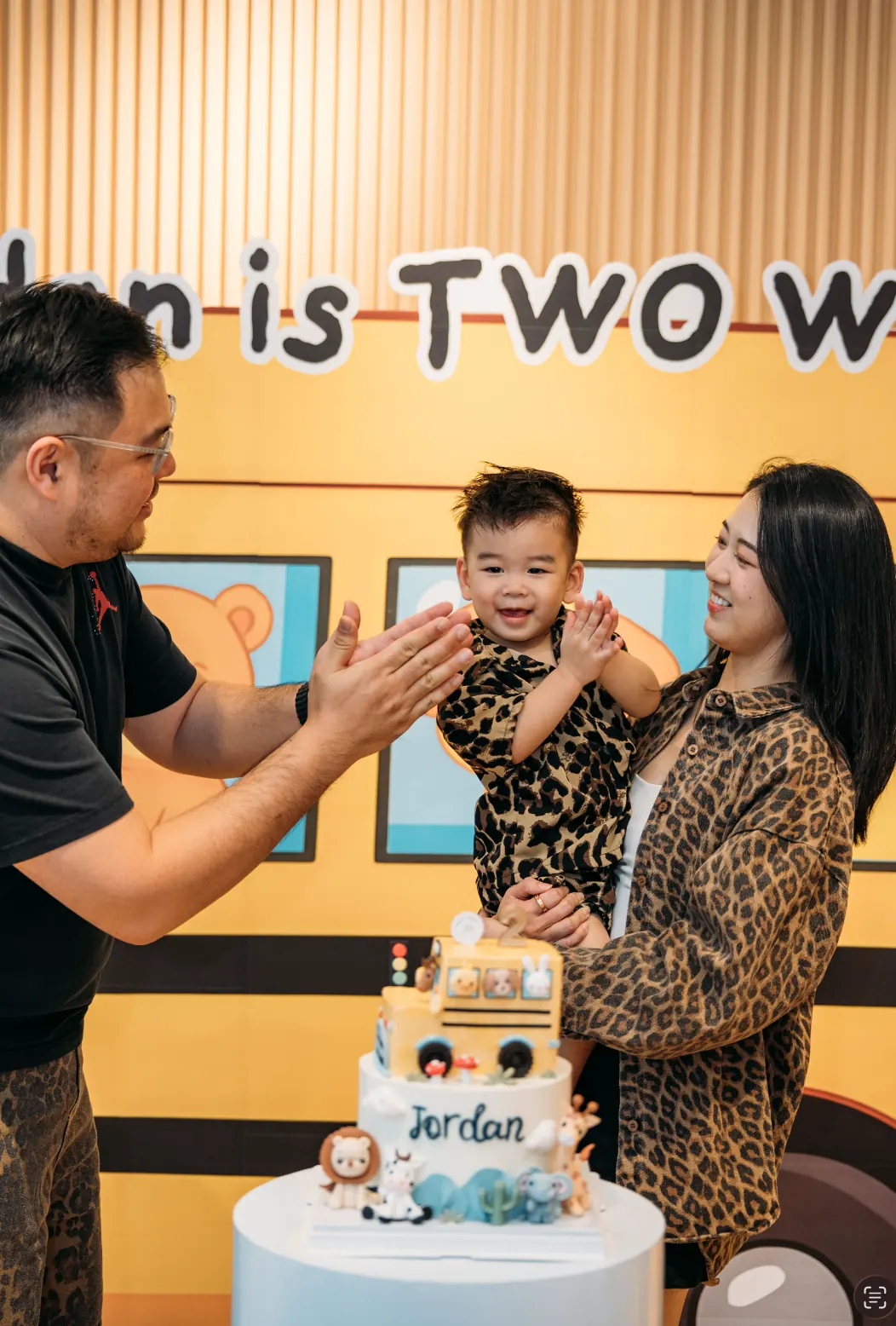 Jordan clapping between both his parents at his second birthday party at Naru.