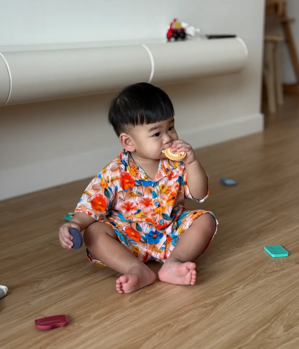 Jordan sitting on the floor among a spread of objects for his zhua zhou ceremony on his first birthday.