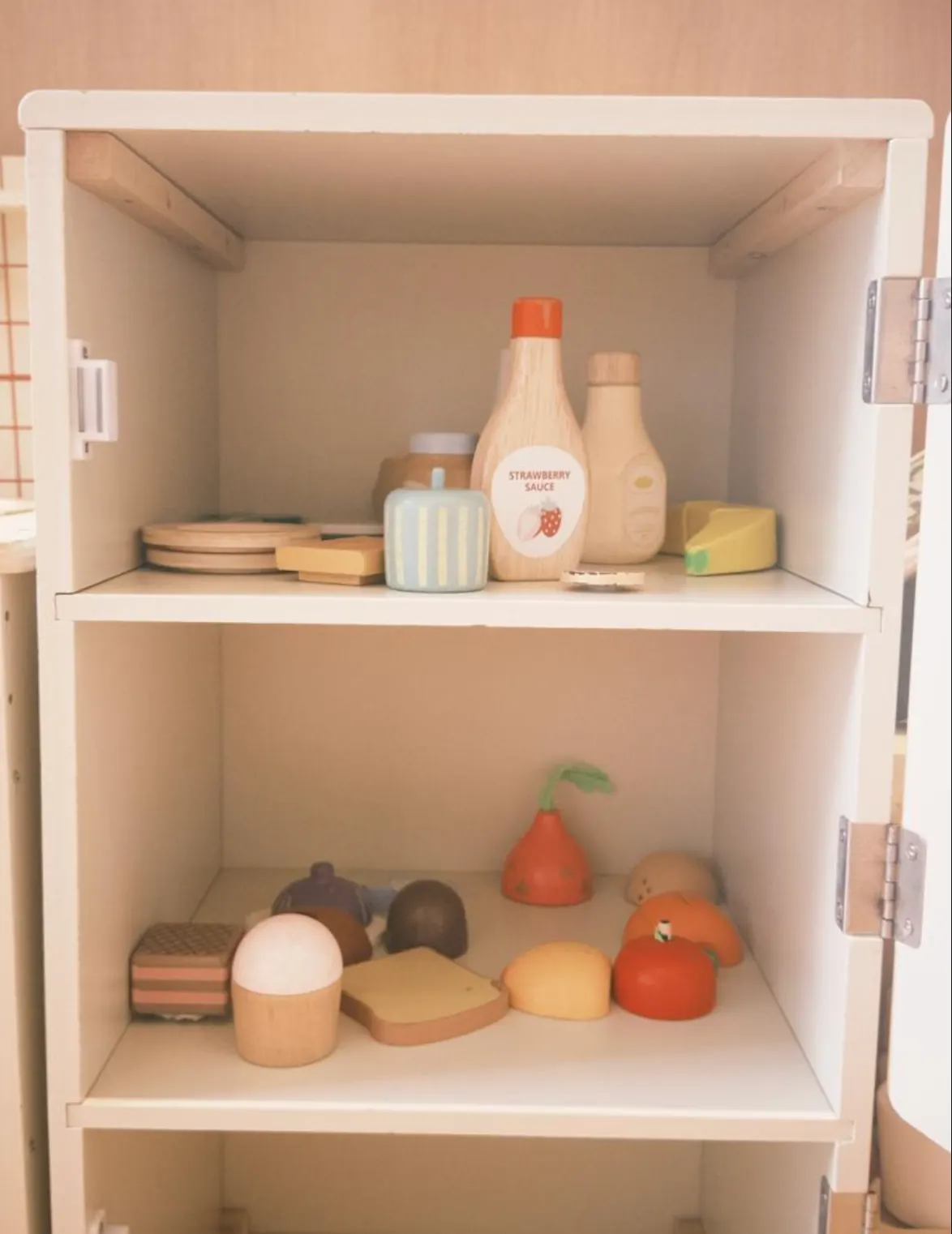 The wooden play fridge at Naru, every piece of wooden food packed neatly inside by the children.
