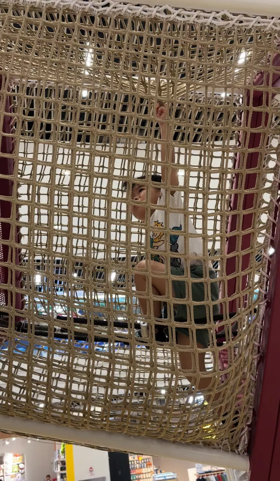 The same toddler, weeks later, confidently climbing a much larger net-and-rope structure on his own.