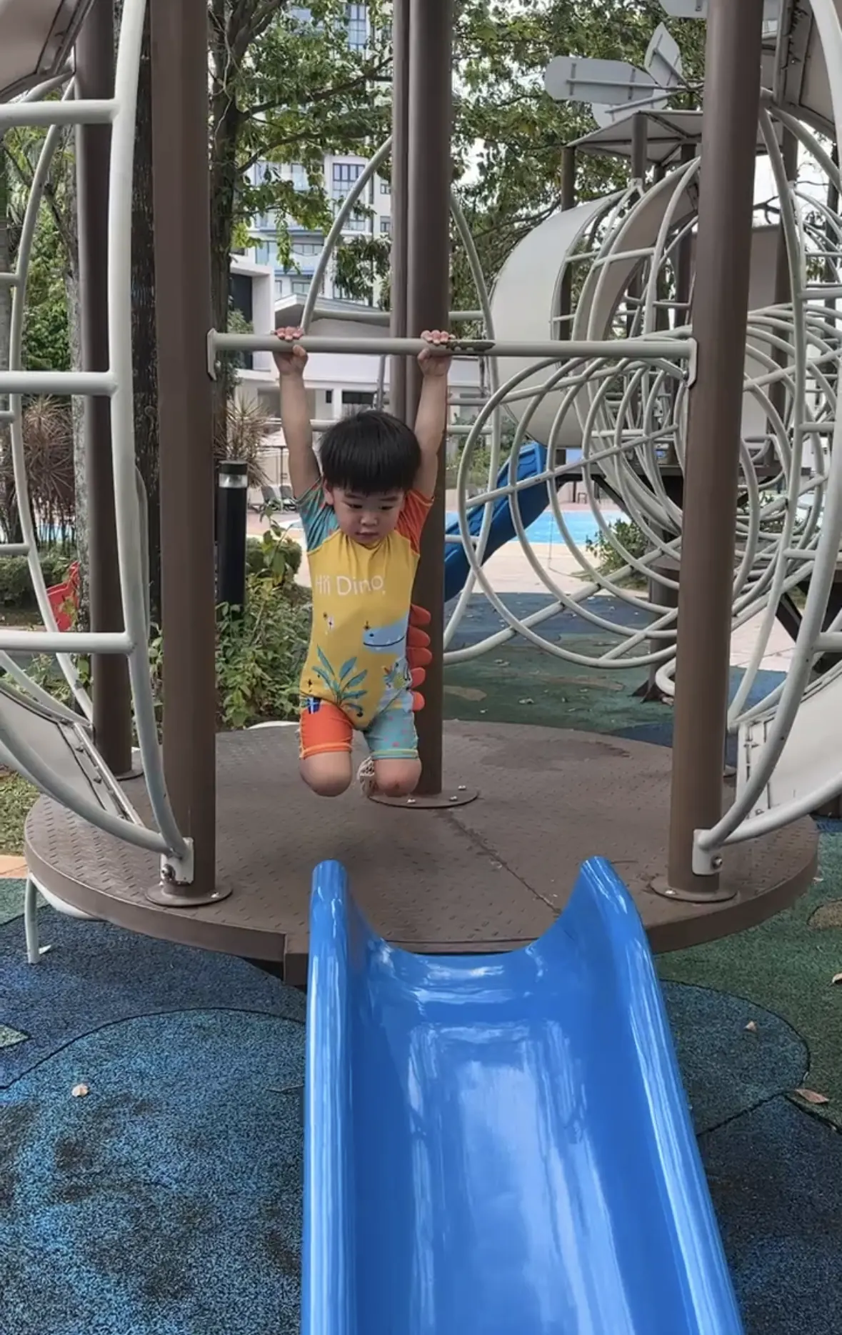 A toddler carefully climbing a structure one bar at a time, with a parent close by.